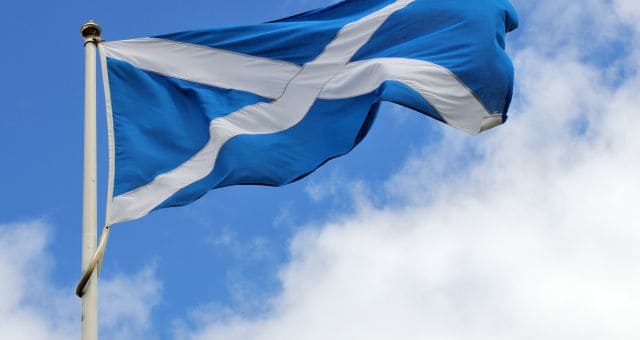An image of a Scottish flag blowing in the wind in the sky.