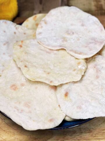 Three ingredient flatbreads in a pile on a wooden table,
