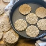 vegan oatcakes in cast iron skillet, with cooked oatcakes to side.