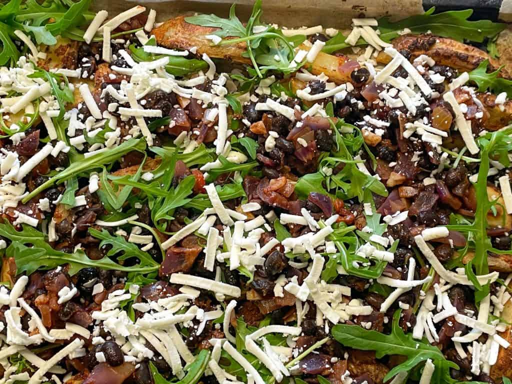 loaded black bean potatoes uncooked on baking tray. with vegan shredded cheese.