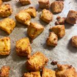 vegan crispy tofu bites sitting on greaseproof paper on baking tray.