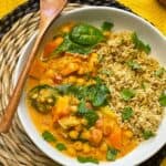 Thai red curry served in bowl with wooden spoon to side, and wicker table mat.