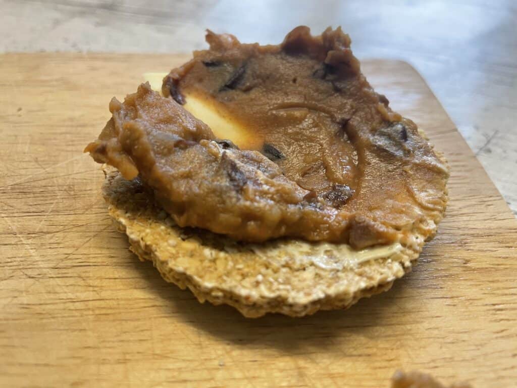 vegan Scottish oatcakes topped with refried beans, light wooden table background.