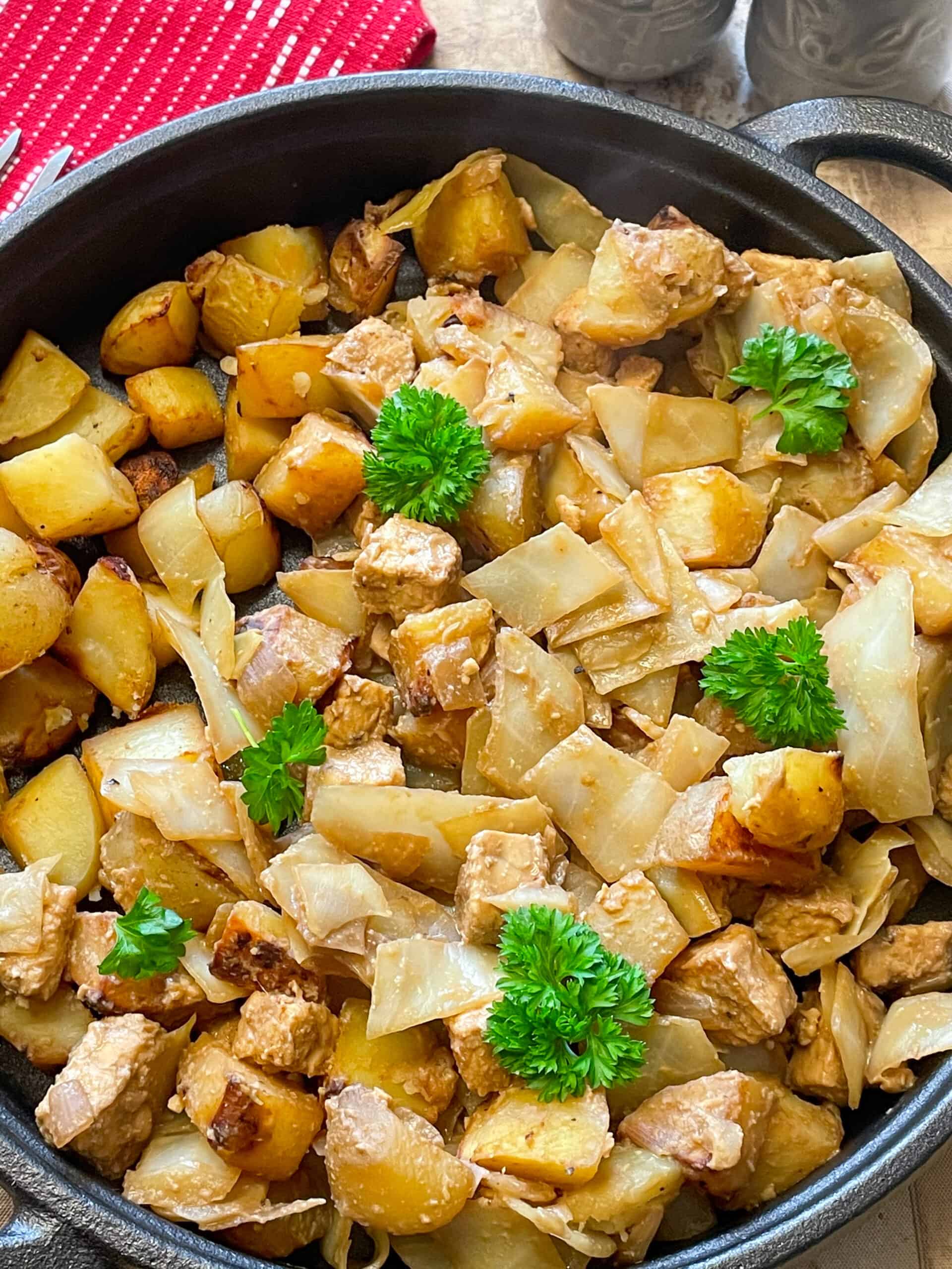 Roast potatoes added to cooked vegan hash in pan and garnished with parsley