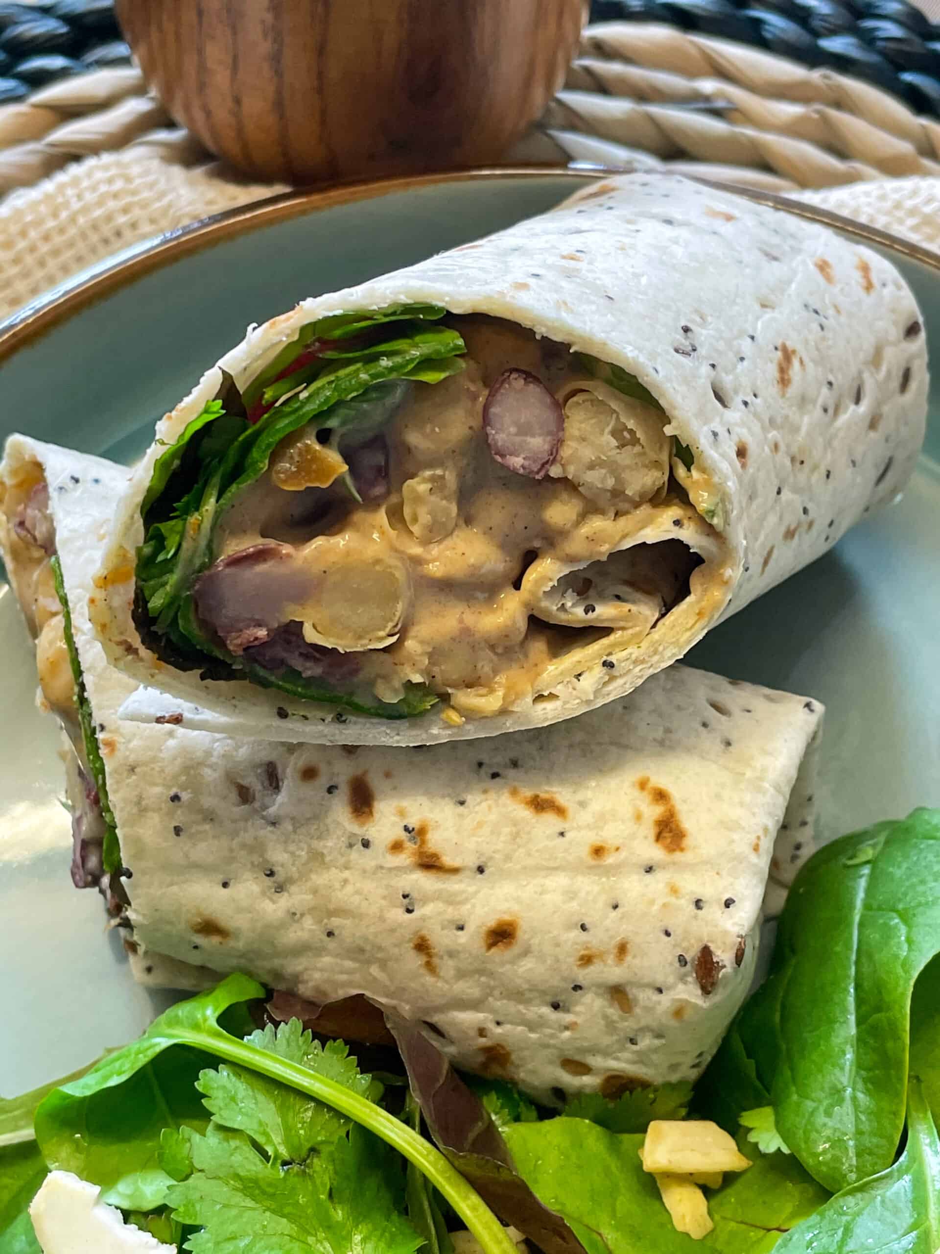 tortilla wrap halved into two pieces, one piece on the side of the other, sitting on green plate.