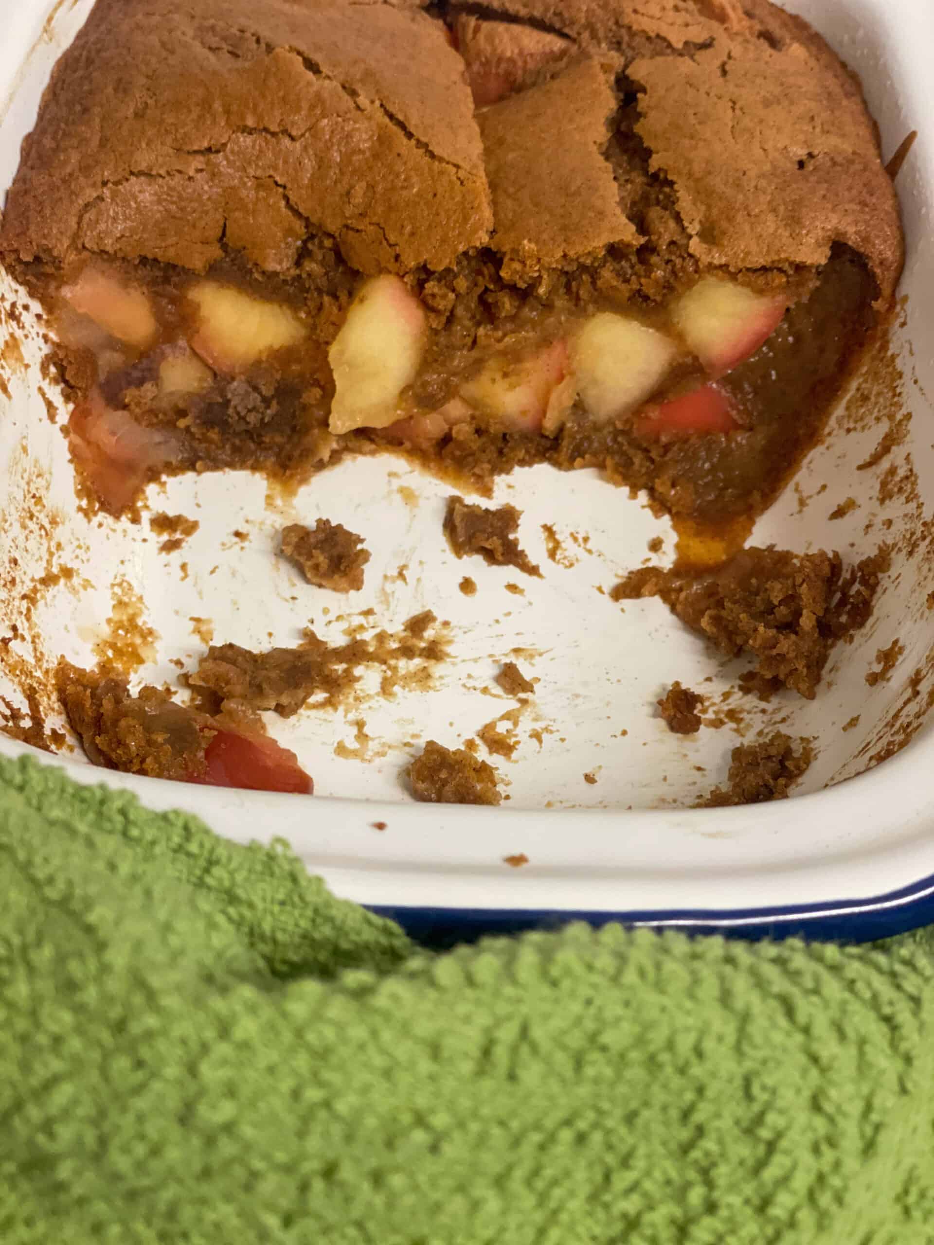 Eve's pudding with half removed from dish, green tea cloth background.