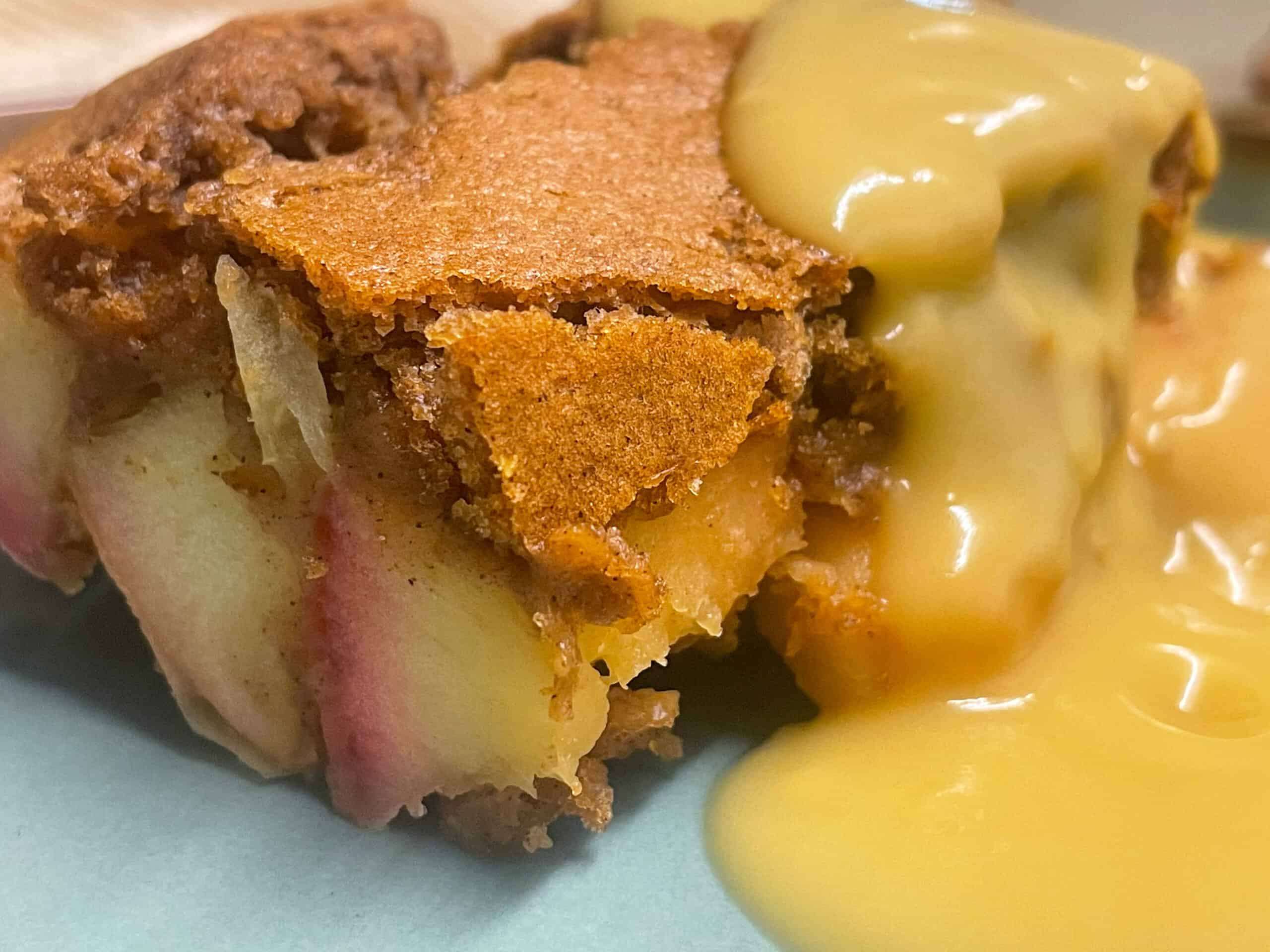 Vegan eve's pudding with custard on a blue plate.