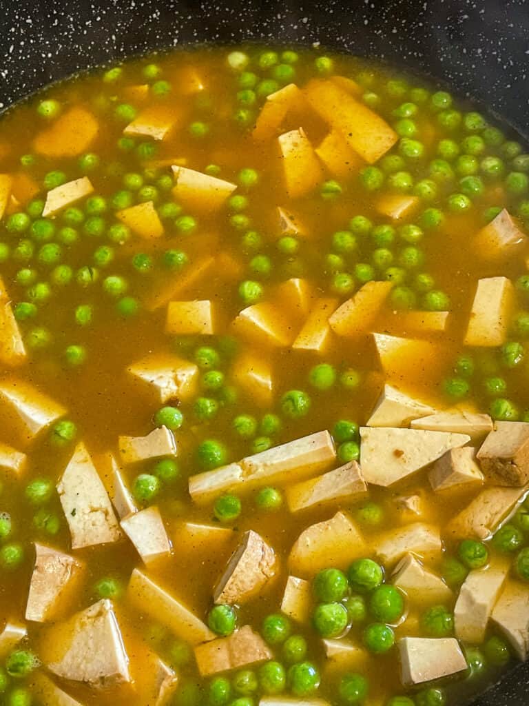 vegan smoked tofu kedgeree with veggie stock added cooking in a pan.