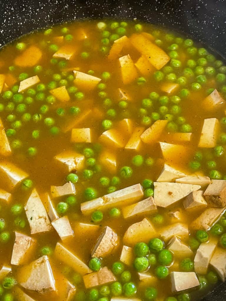 smoked tofu kedgeree with veggie stock added cooking in a pan.