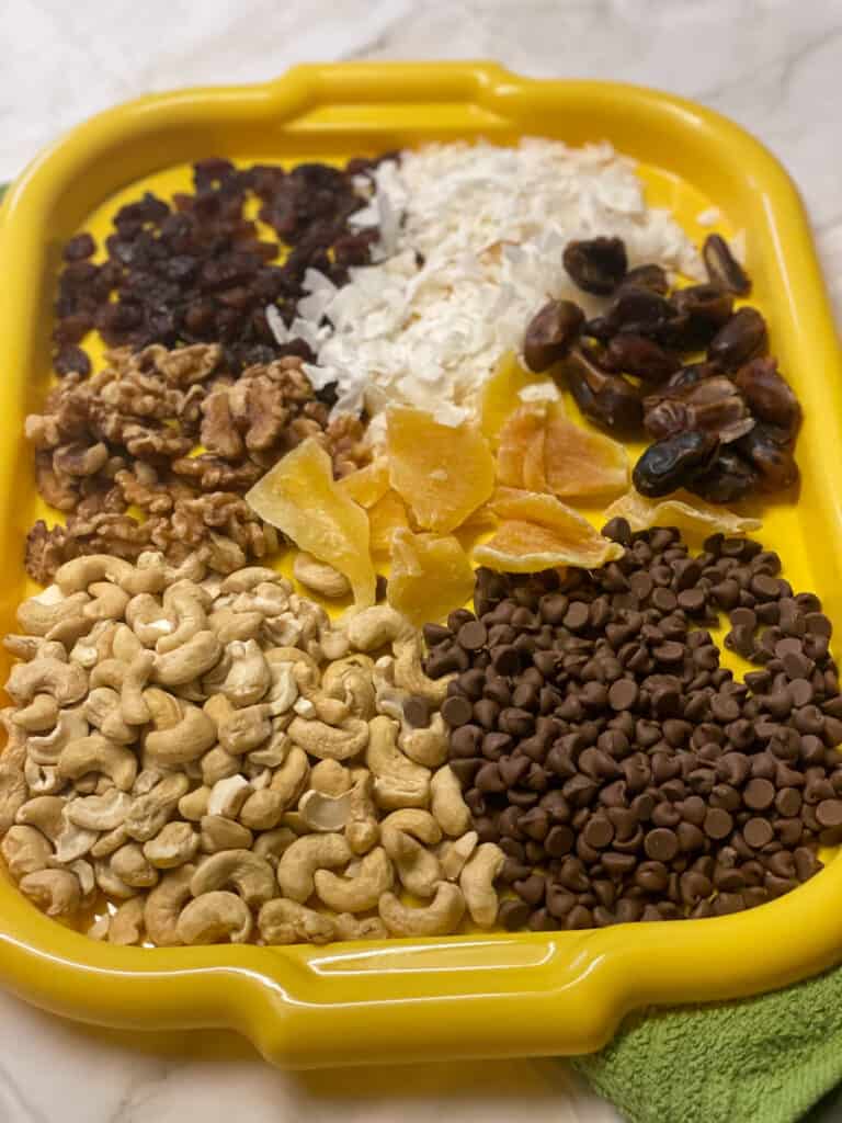 vegan trail mix ingredients set out on yellow tray.