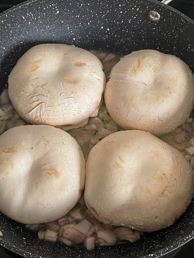 4 large mushrooms in the pan with shallots.