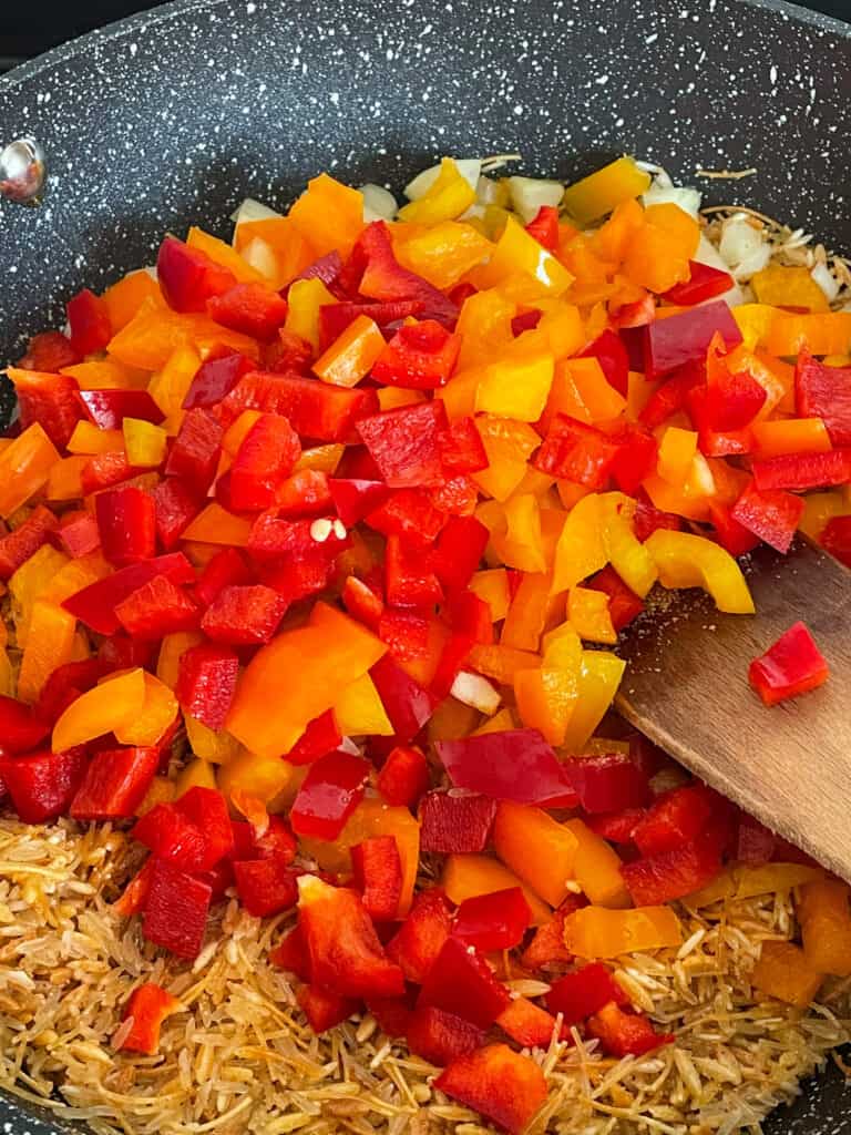 bell peppers added to pan of rice, orzo and pasta.