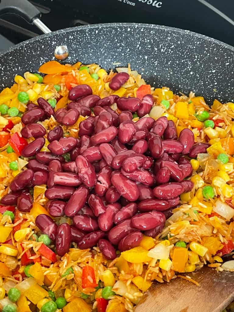 kidney beans added to vegan rice-a-roni cooking in pan.