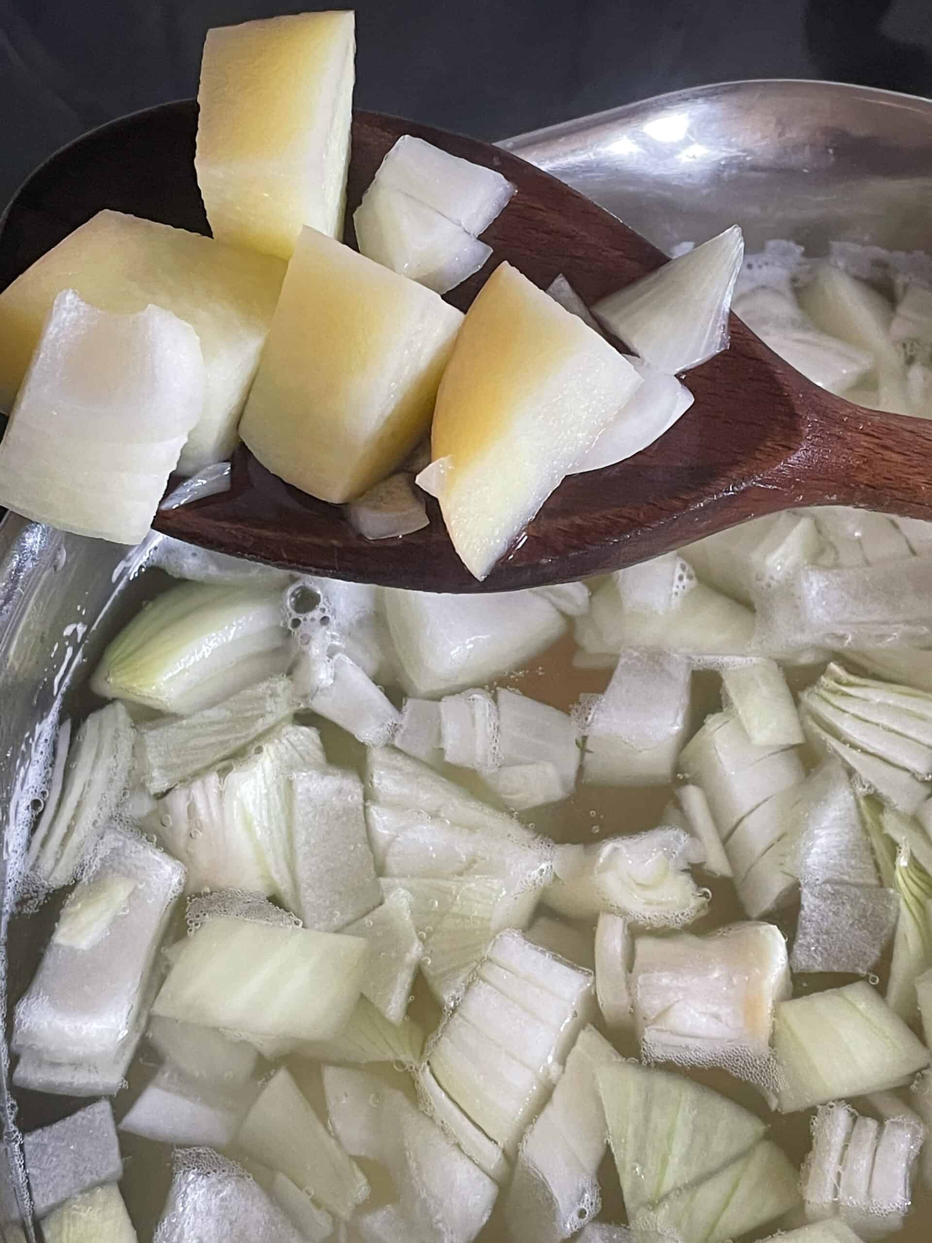 Potatoes and onions for filling in saucepan with wooden spoon.