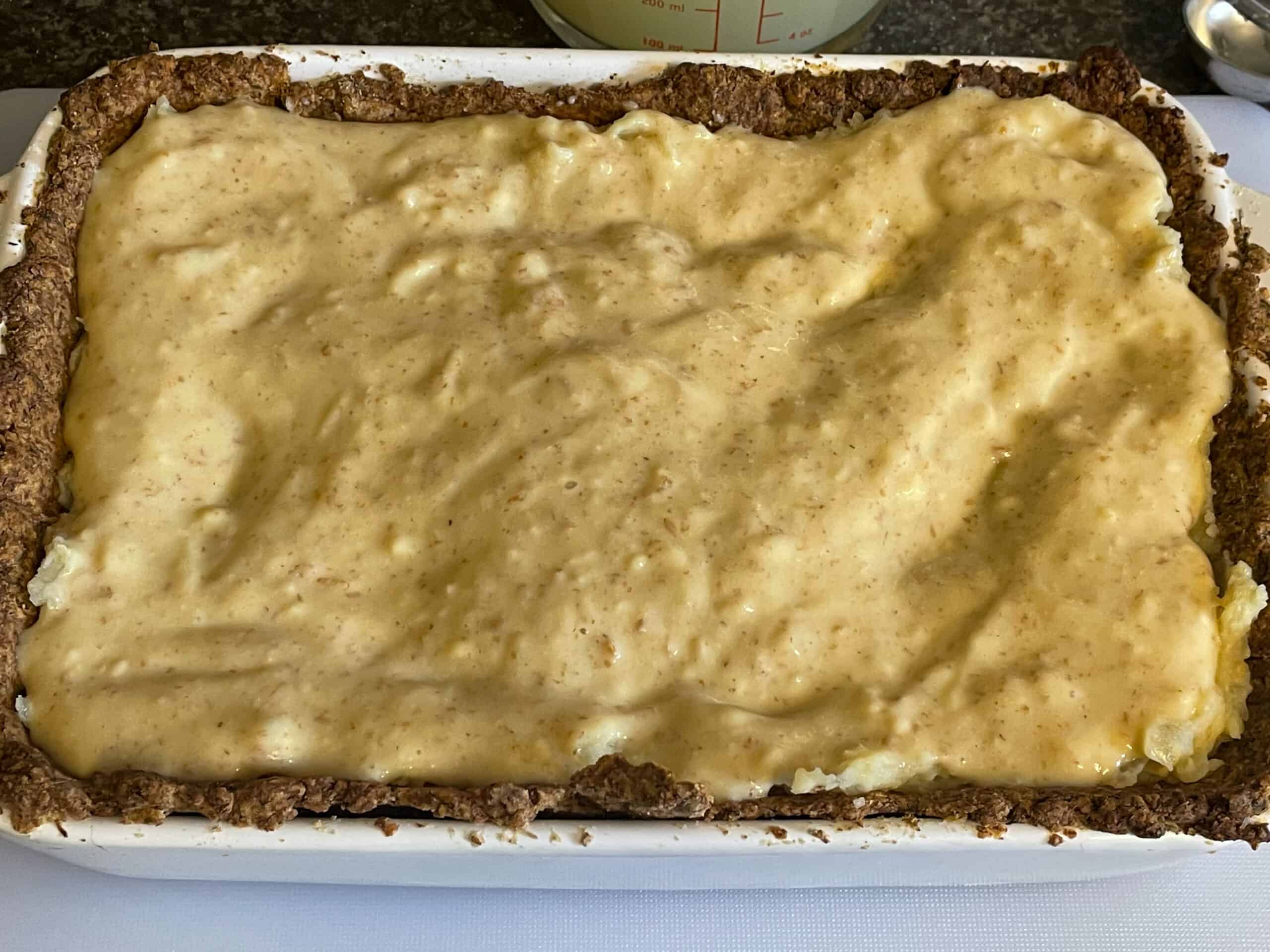 Potato filling added to baked pie crust and topped with cheese sauce.