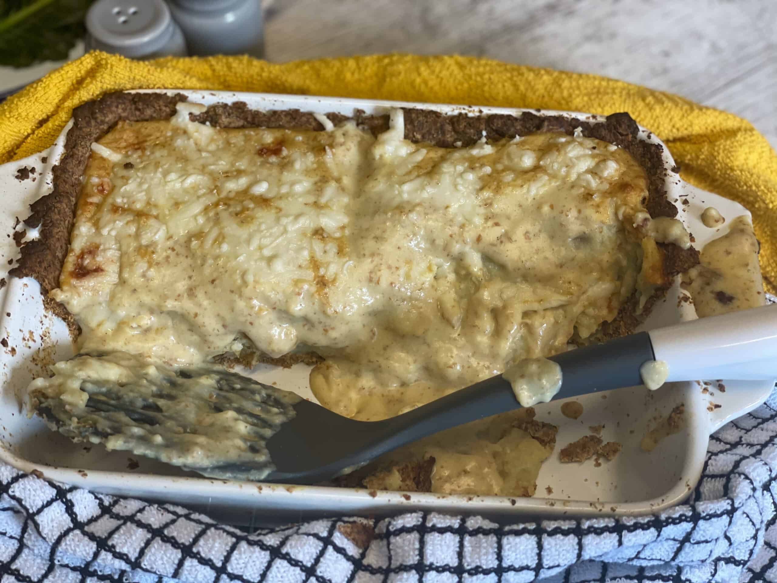 Pie served up with slices removed in baking pan, with spatula, yellow and blue check white tea towel.