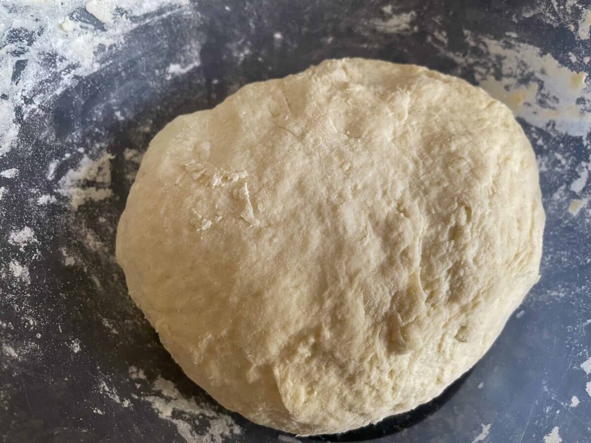 Vegan 3 ingredient flatbread dough prepared and on a floury black chopping board.