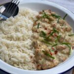 Vegan butterbean chicken supreme with white boiled rice served on a white bowl with a spoon and fork displayed at the side