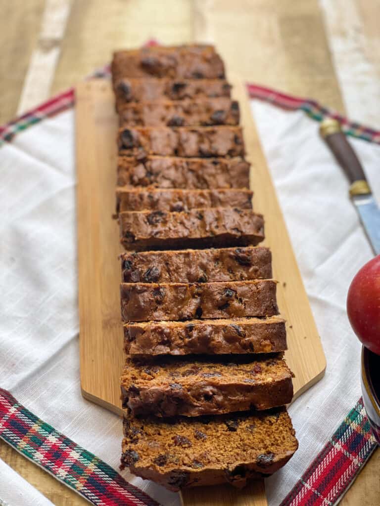 vegan fruit loaf cake on wooden board and sliced into 13 pieces