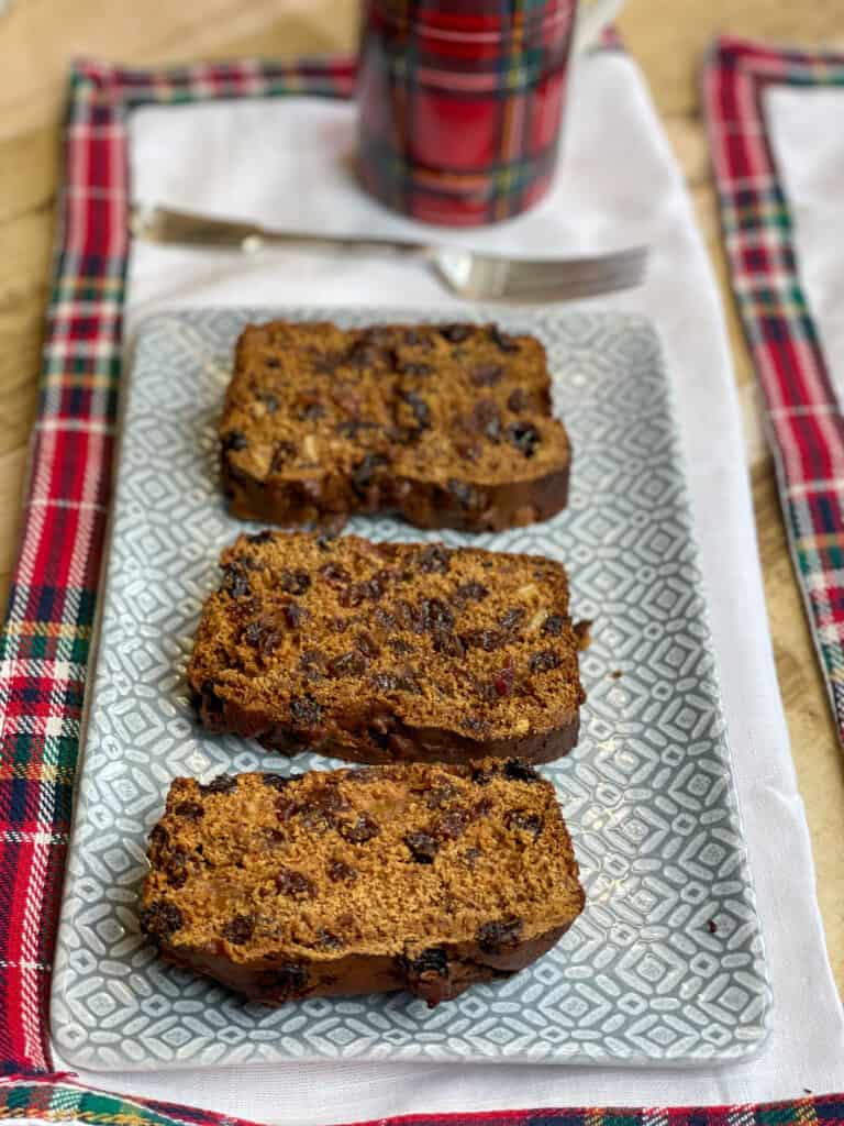 vegan fruit loaf cake on grey plate with fork and tartan cup