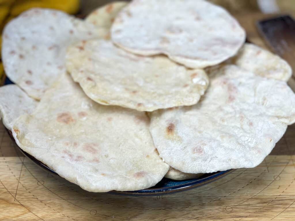 vegan 3 ingredient flatbreads ready and sitting on a plate on top of a wooden board