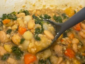 potage stew ready to serve and being scooped up with a grey ladle.