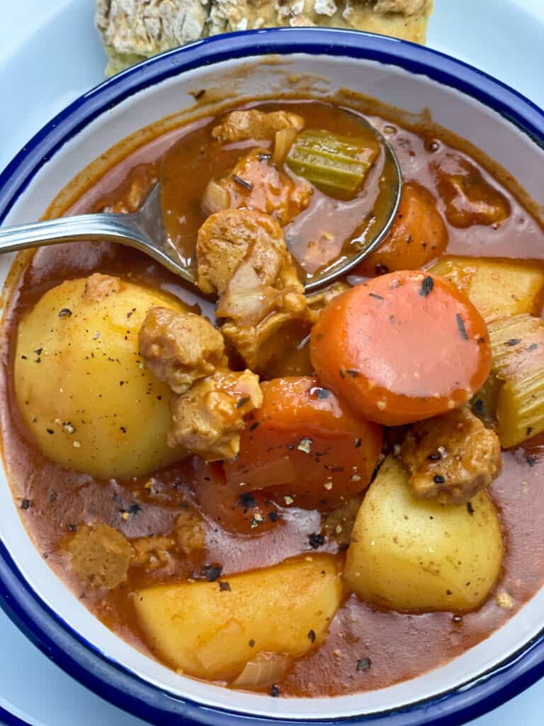 beef stew served up in white bowl with silver spoon.