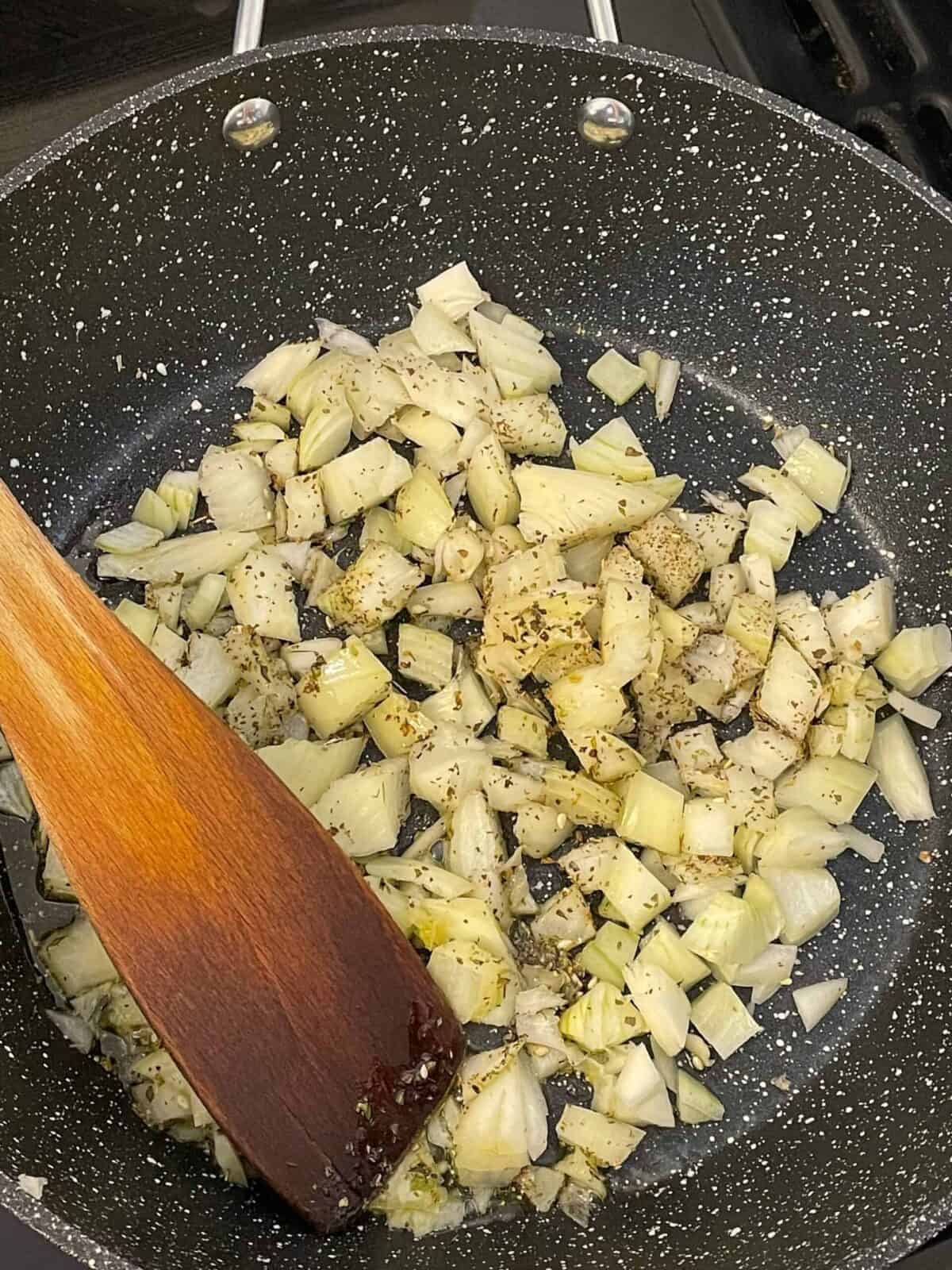 Chopped onions and mixed herbs cooking in skillet.