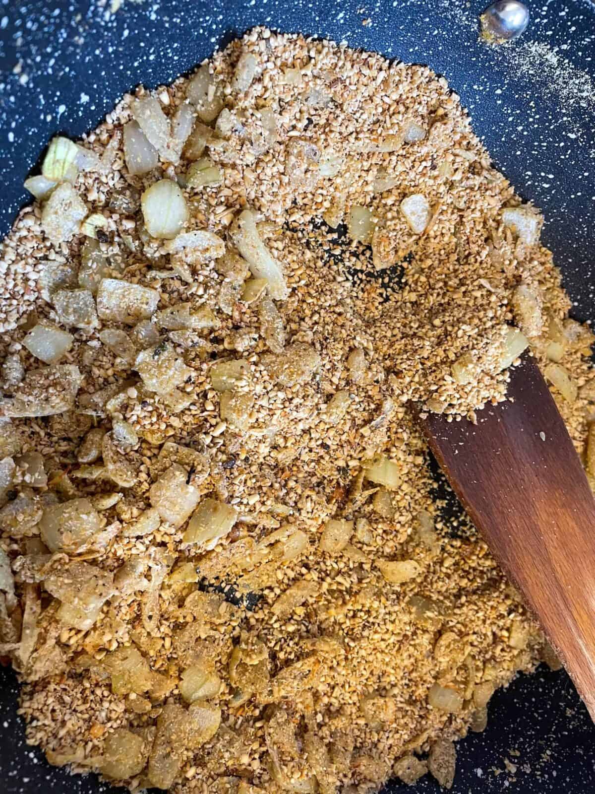 Skirlie cooking in pan with wooden spatula.