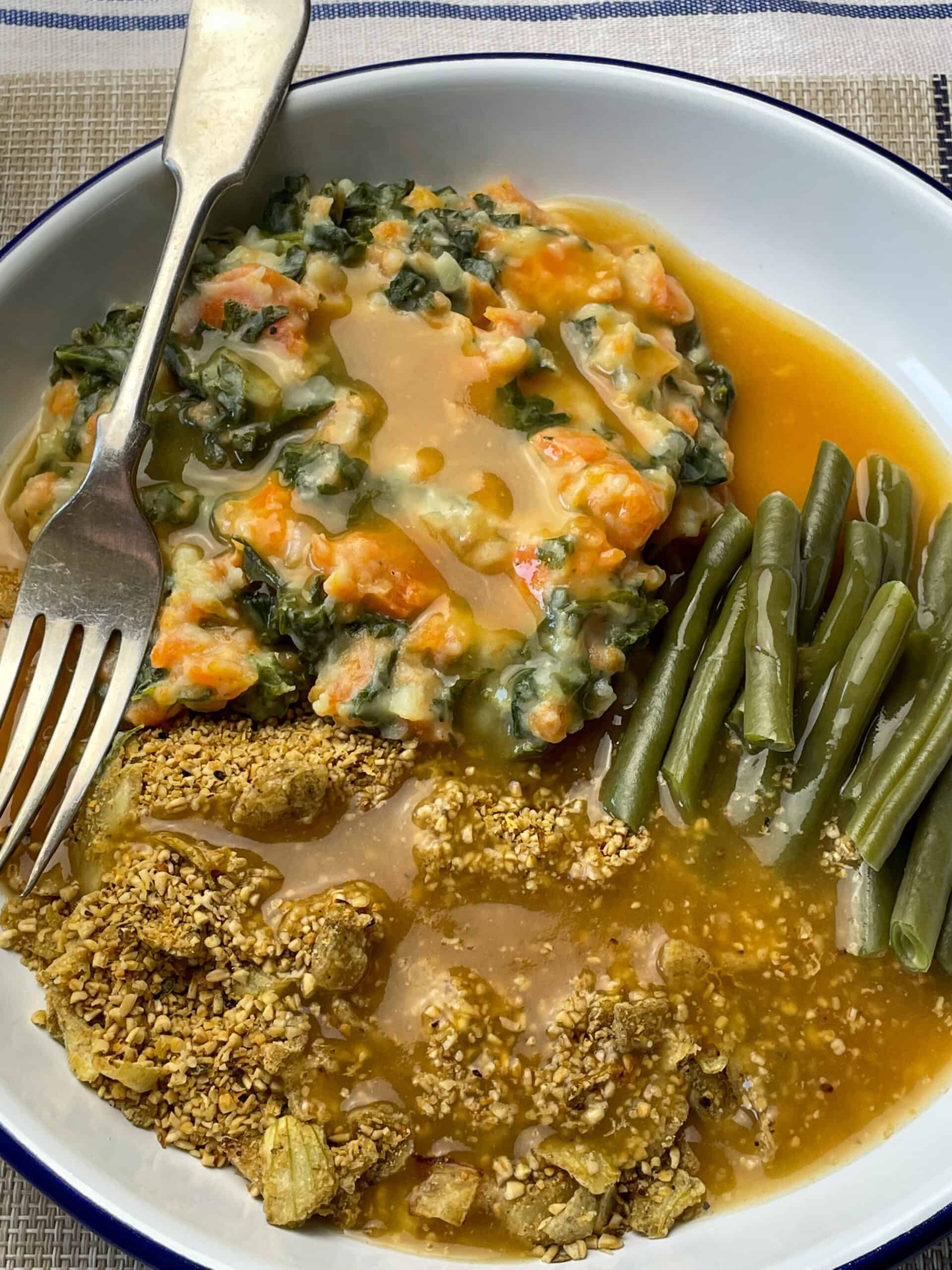 Vegan Scottish skirlie served with gravy, green beans and veggie mash, fork to the side.