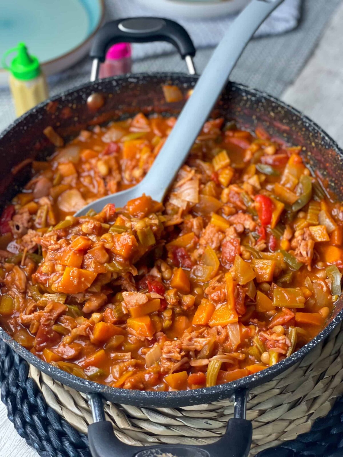 Campfire stew in skillet pan with ladle, basket table mat background.