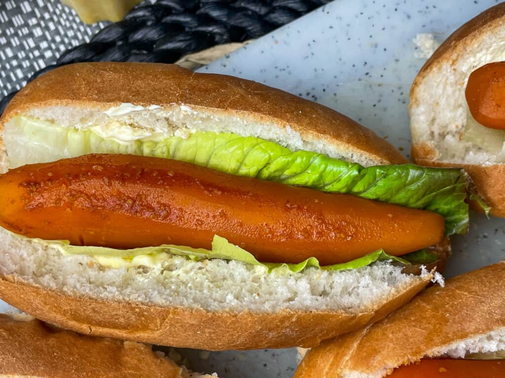 carrot dog added to hotdog bun with lettuce leaf.