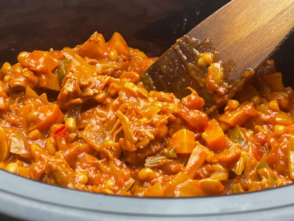 camp fire stew in the slow cooker with a mixing spoon.