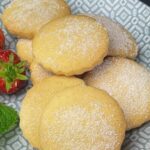 Plate of shortbread biscuits on grey plate with strawberries and a mint leaf at the side.