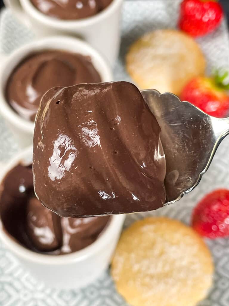 close up of chocolate pudding with chocolate pudding in background, and shortbread biscuits and strawberries in background.