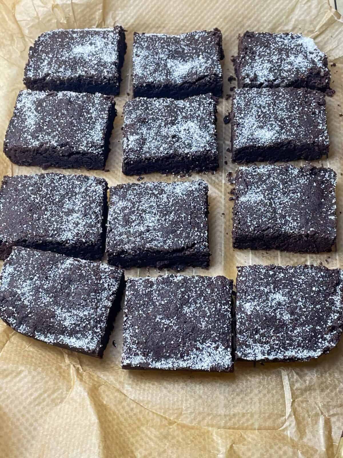 Chocolate concrete cake sliced into pieces on baking paper and wire rack.