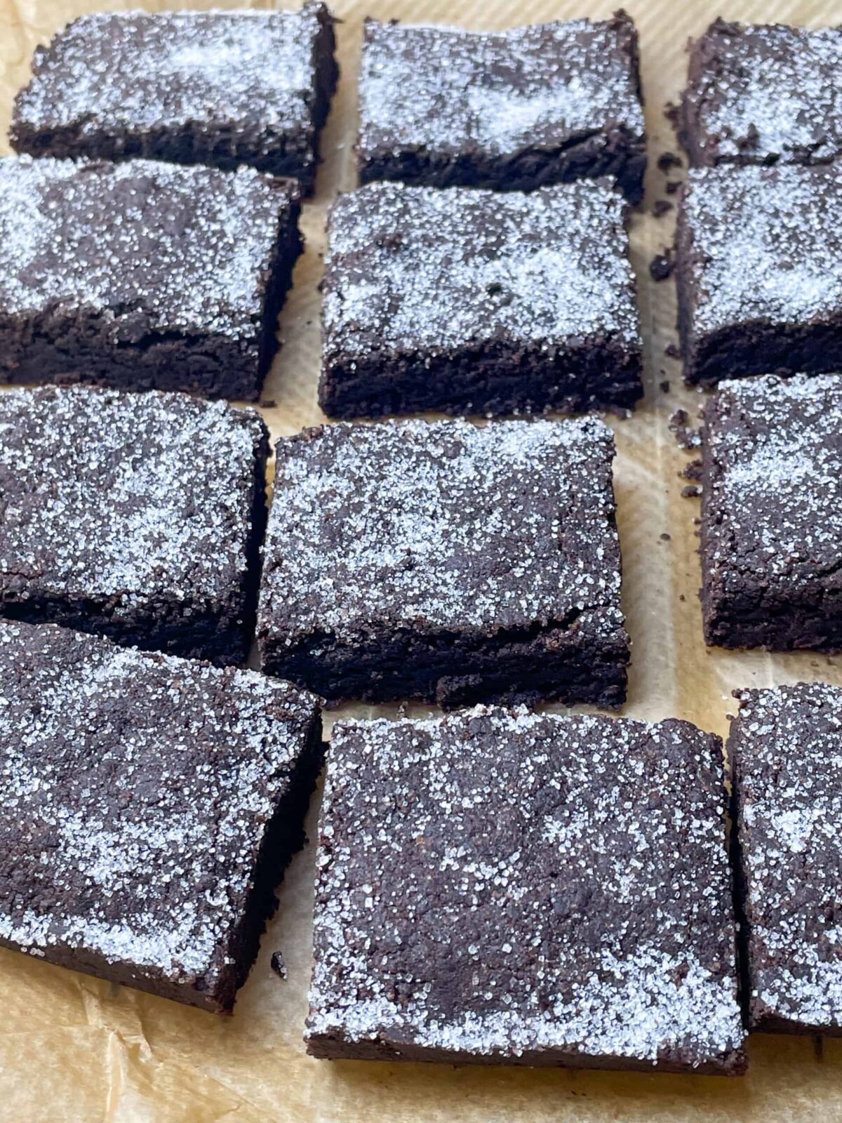 Chocolate concrete cake sliced into 12 pieces, sitting on baking paper.