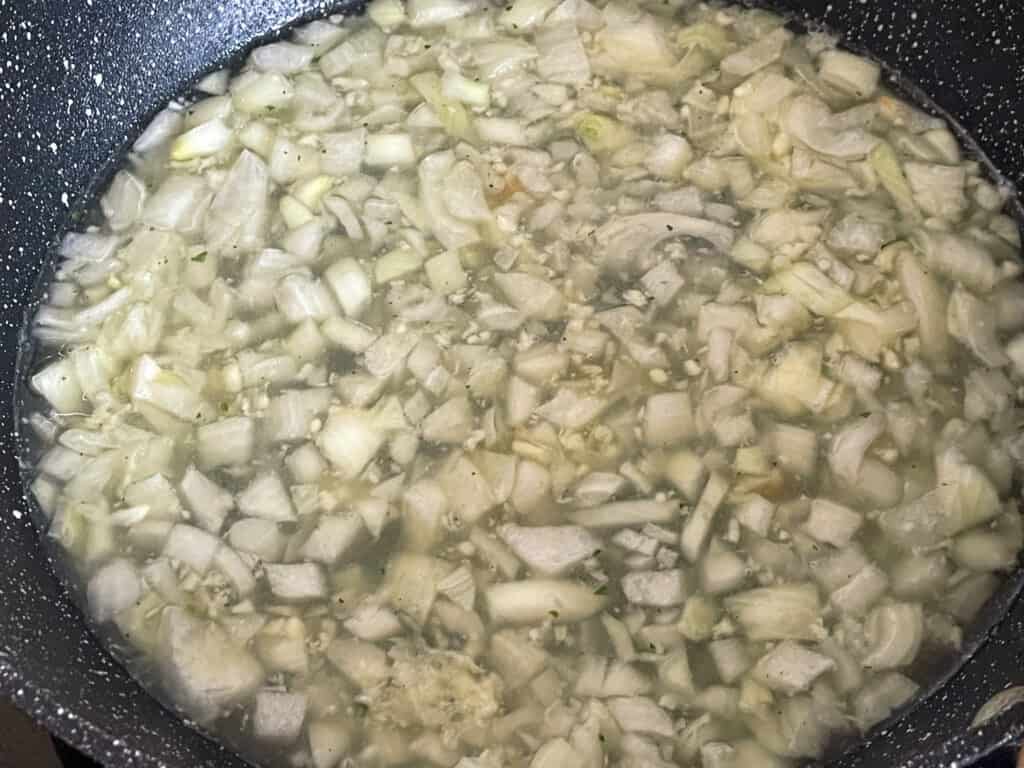 onion and garlic sautéing in veggie stock in skillet pan.