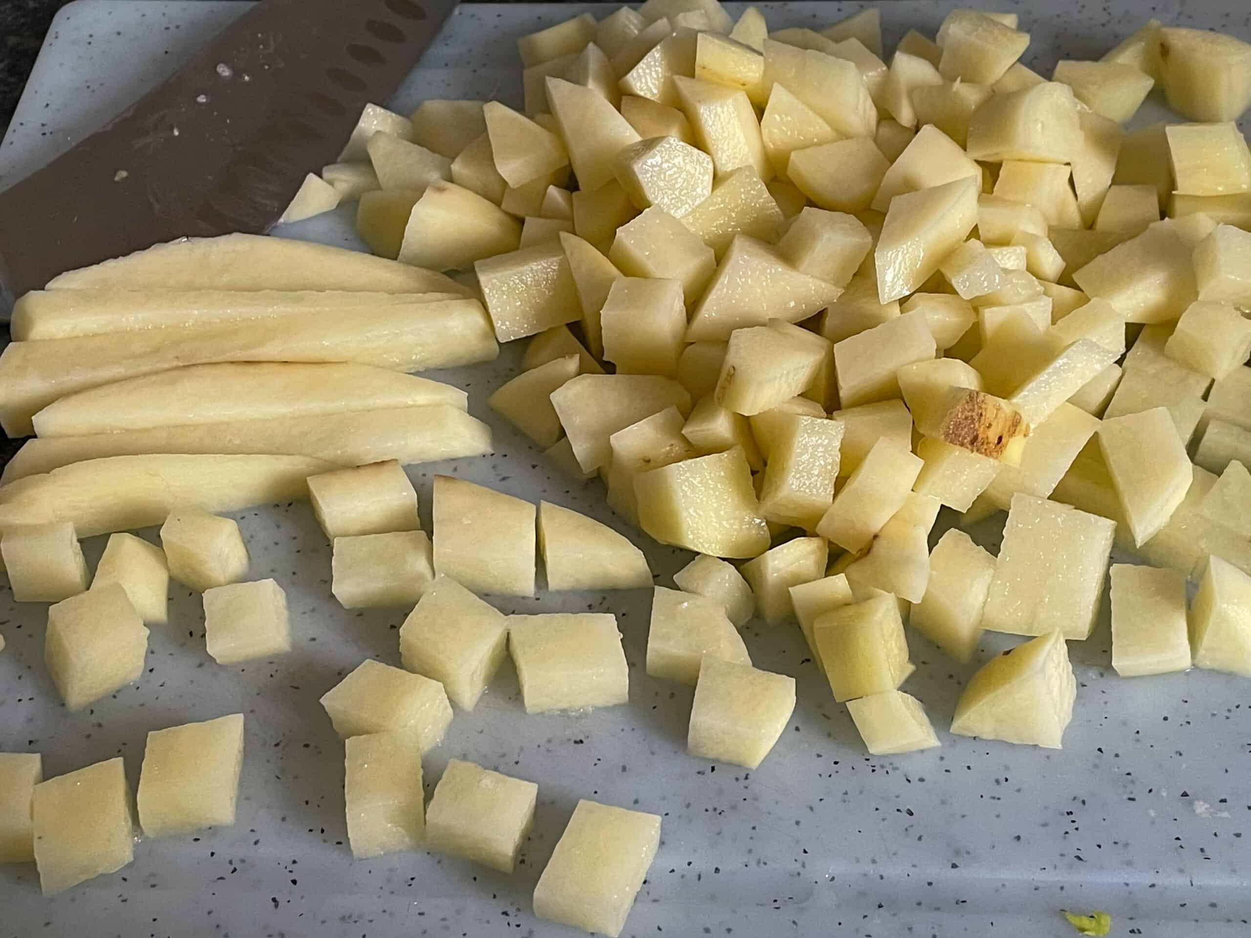 Potatoes chopped into cubes on a chopping board.