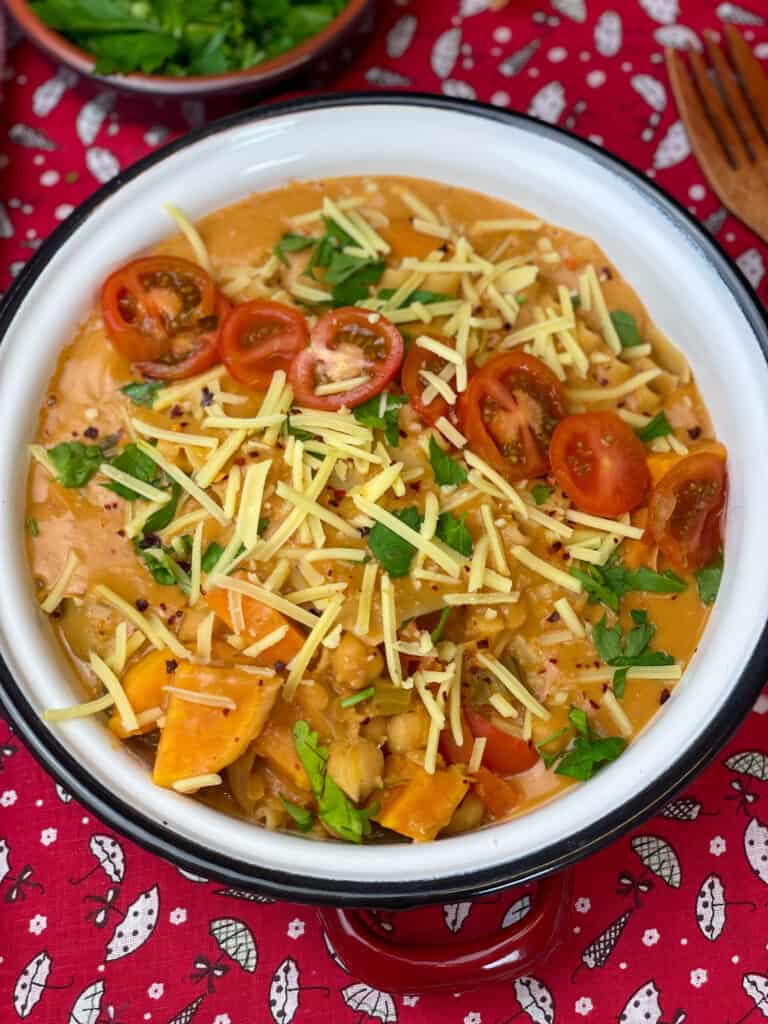 lasagne soup with garnishes and red background.