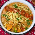 lasagne soup with garnishes and red background.