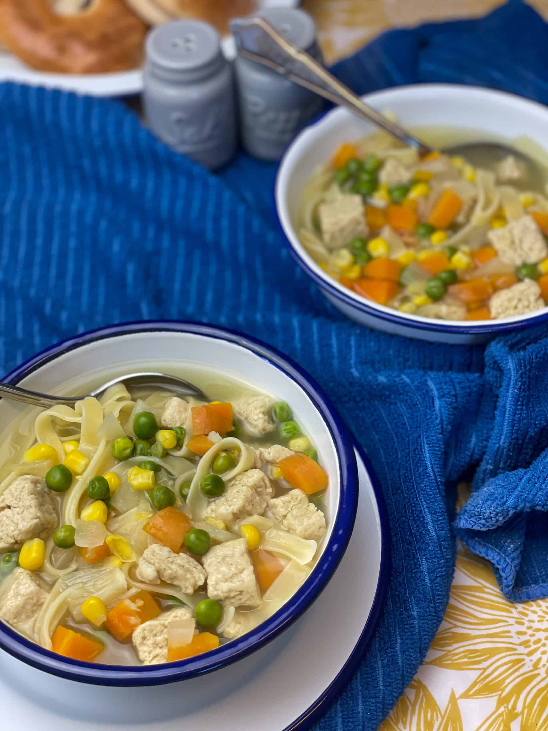 Two bowls of soups with a blue tea cloth background, blue salt and pepper shakes to side.