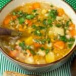 Split pea lentil soup served with crusty bread, green and white spotty tablecloth.