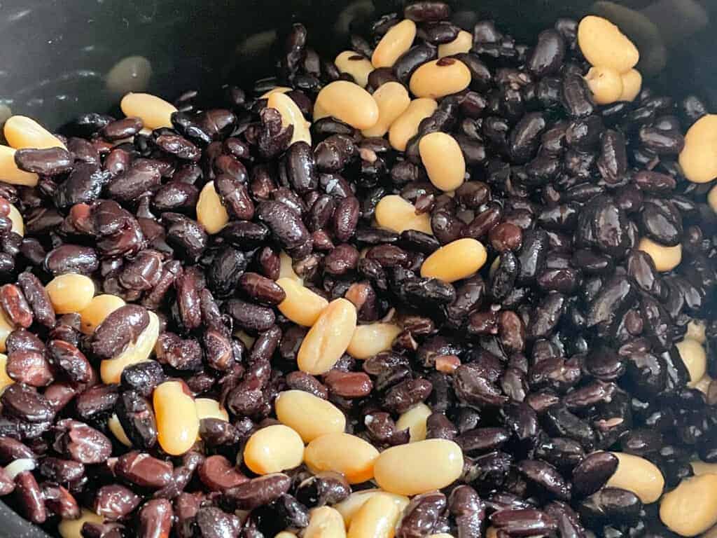 black beans and white kidney beans in slow cooker pot.