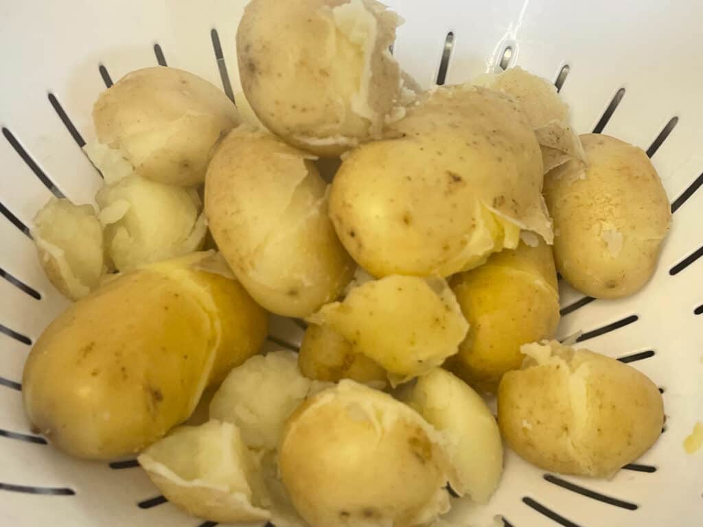 pile of new potatoes cooked in colander.