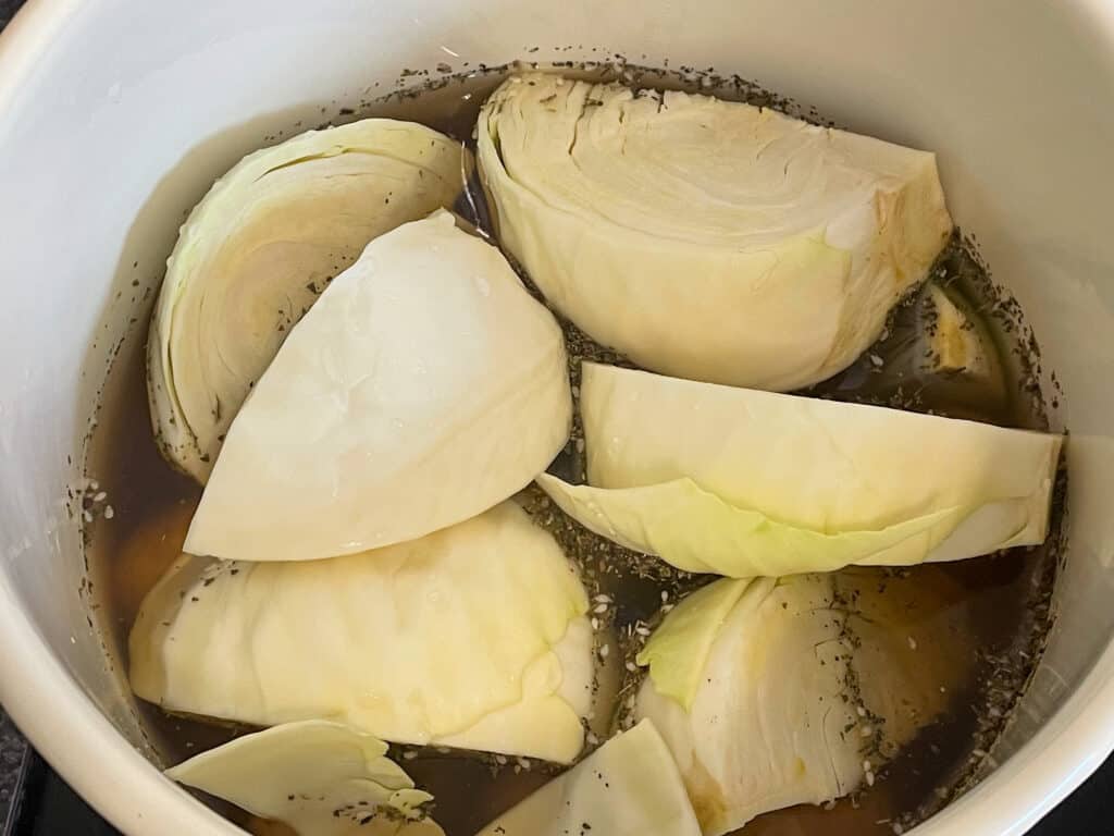 Cabbage wedges added and stock poured into pot.