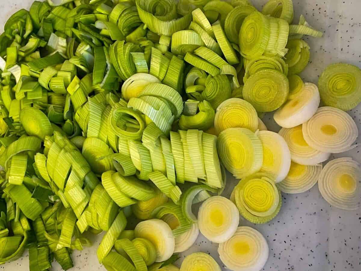 Leeks sliced and on white chopping board.