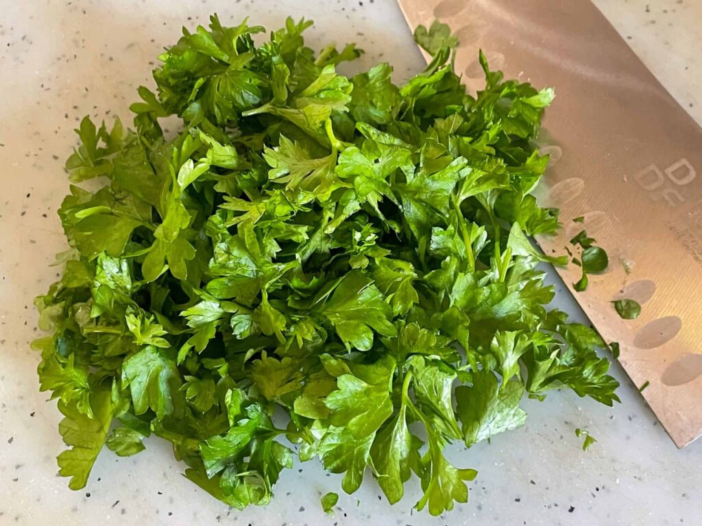 Chopped parsley on chopping board, knife to side.
