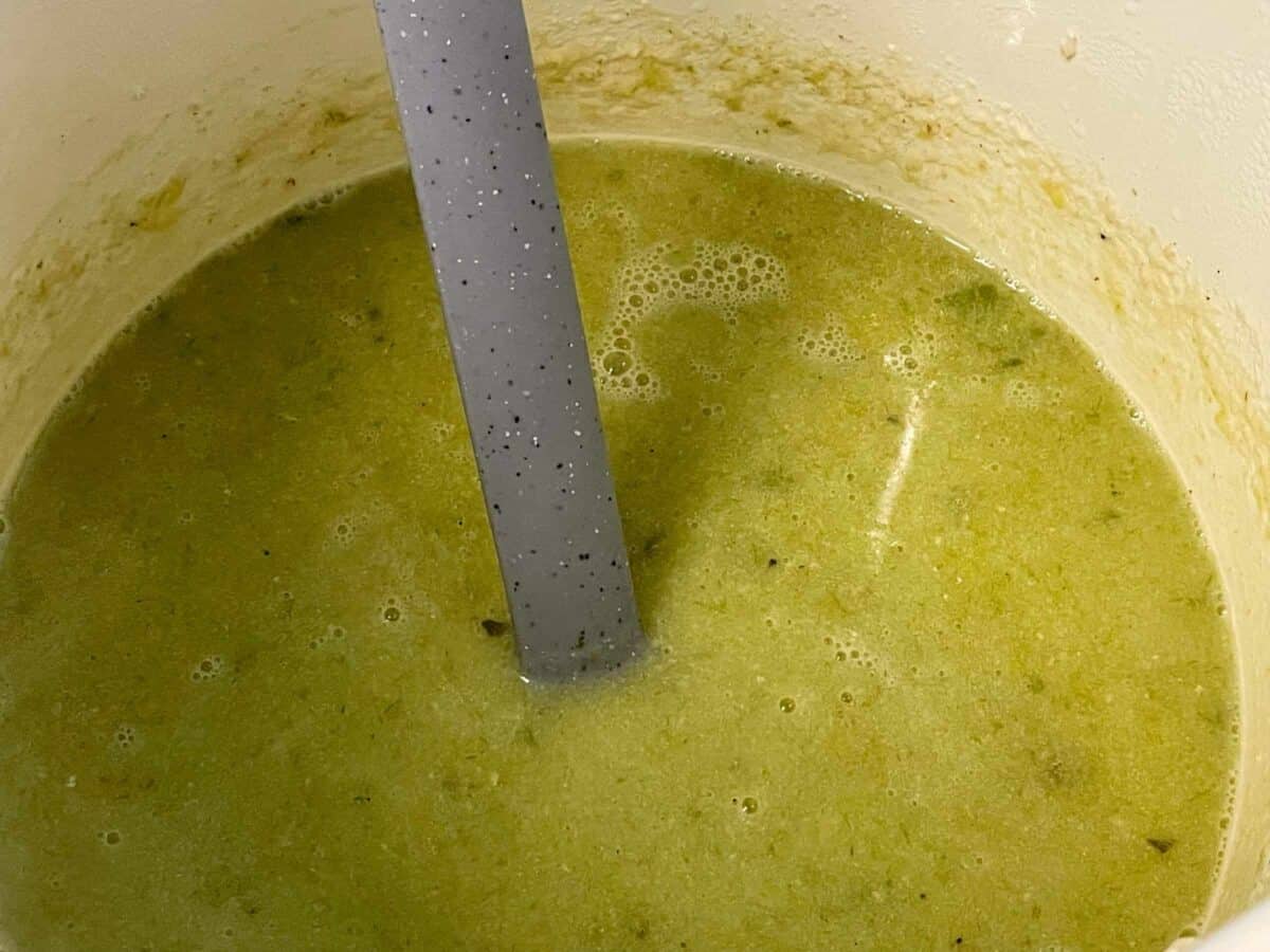 Leek and oatmeal broth blended, grey ladle in soup pan.