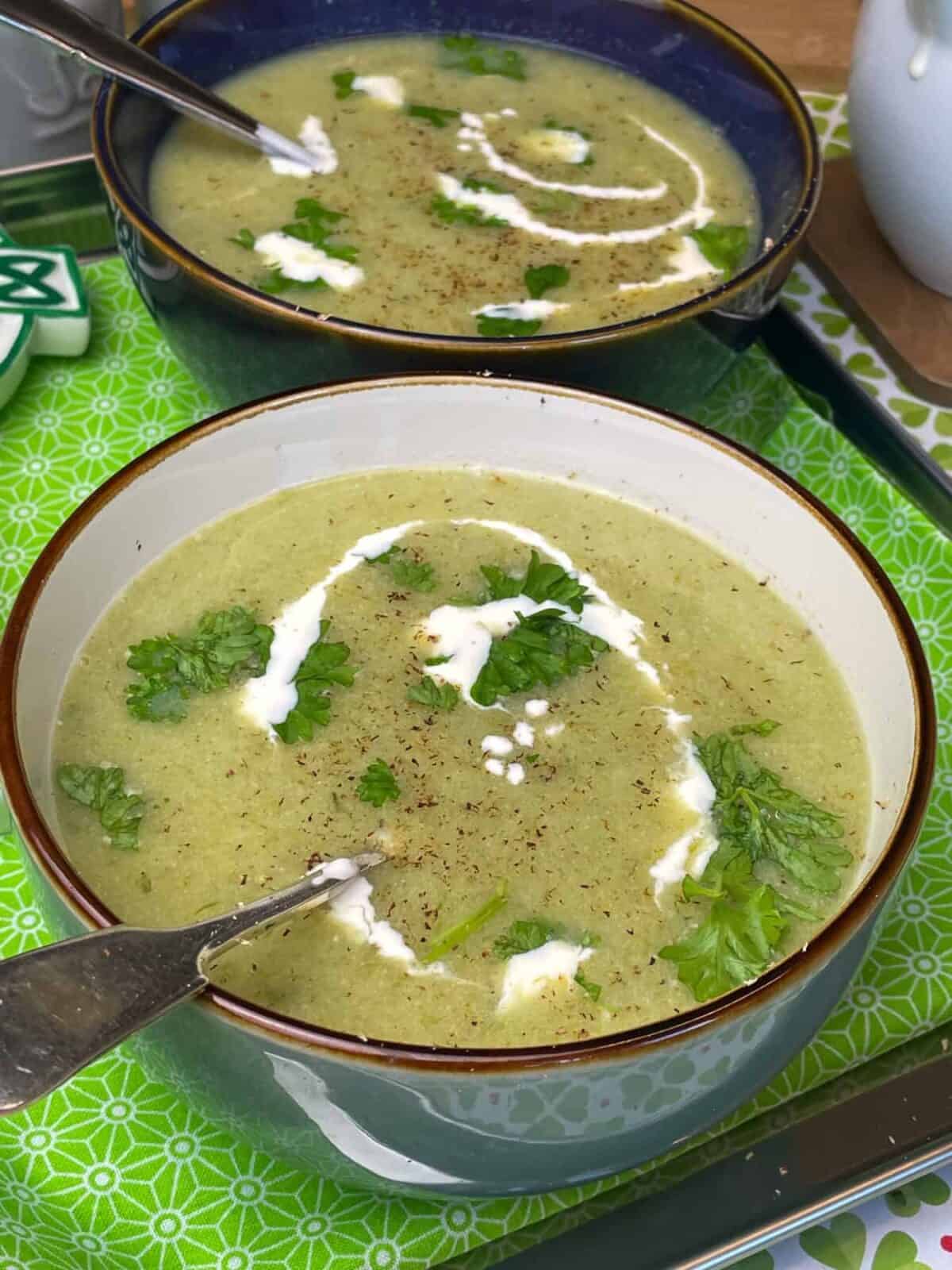 Two bowls of oatmeal soup on a silver tray with a green star table cloth.